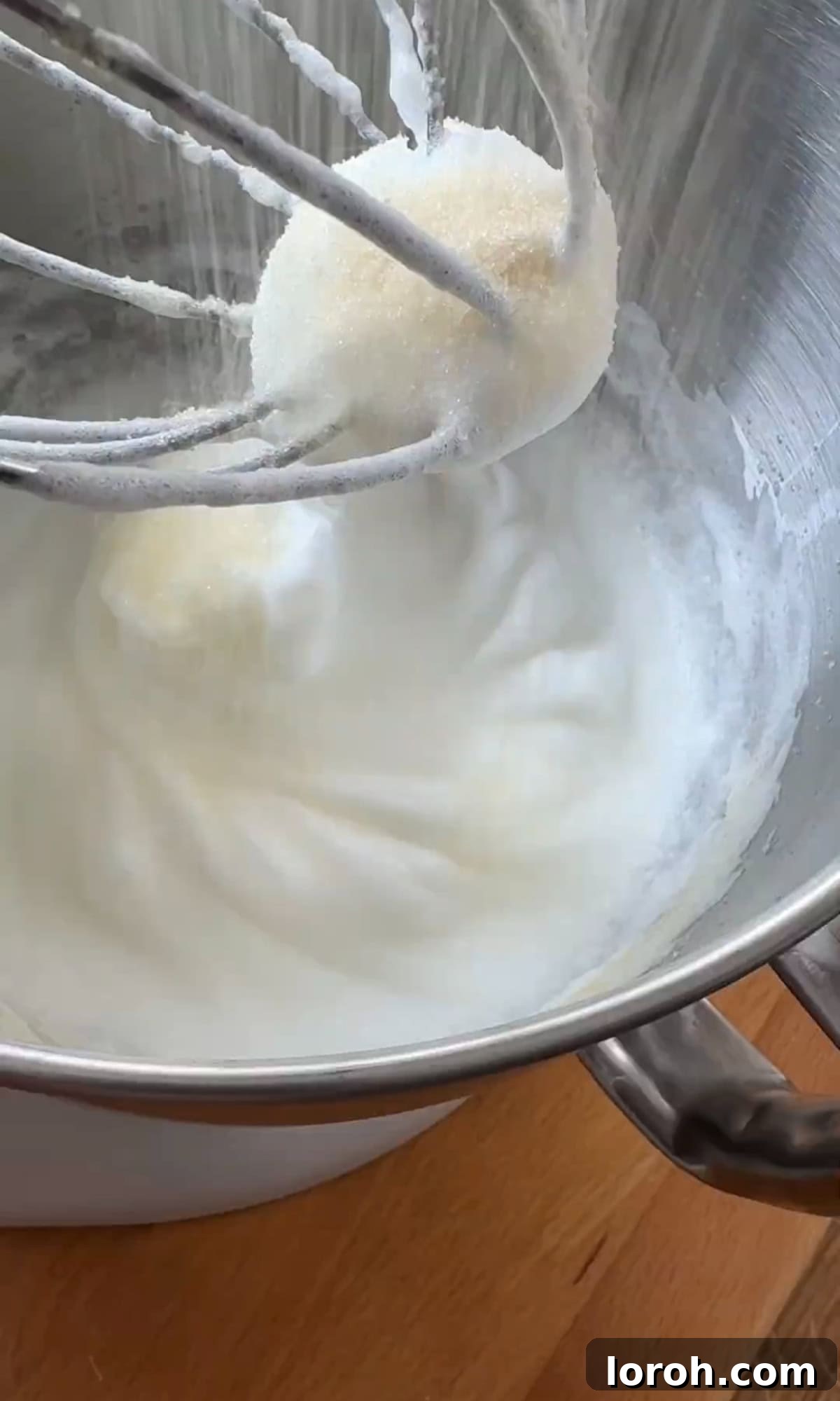 Whisking egg whites to firm peaks in a clean bowl.