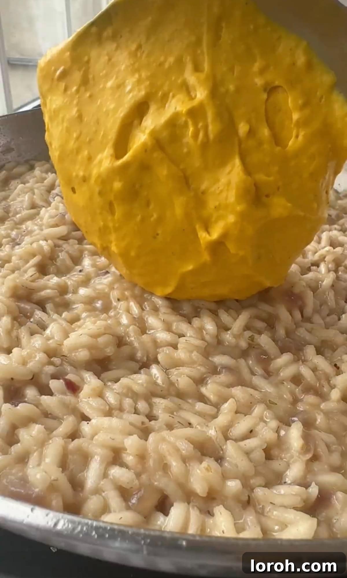 Golden Harvest Pumpkin Risotto 11 Smooth pumpkin purée being stirred into the creamy risotto in a pan.
