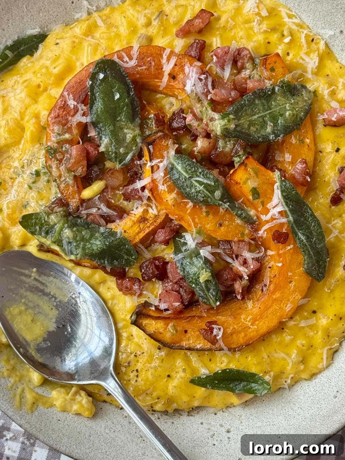A close-up of creamy pumpkin risotto in a grey bowl, highlighting its rich texture and a spoon ready to scoop.