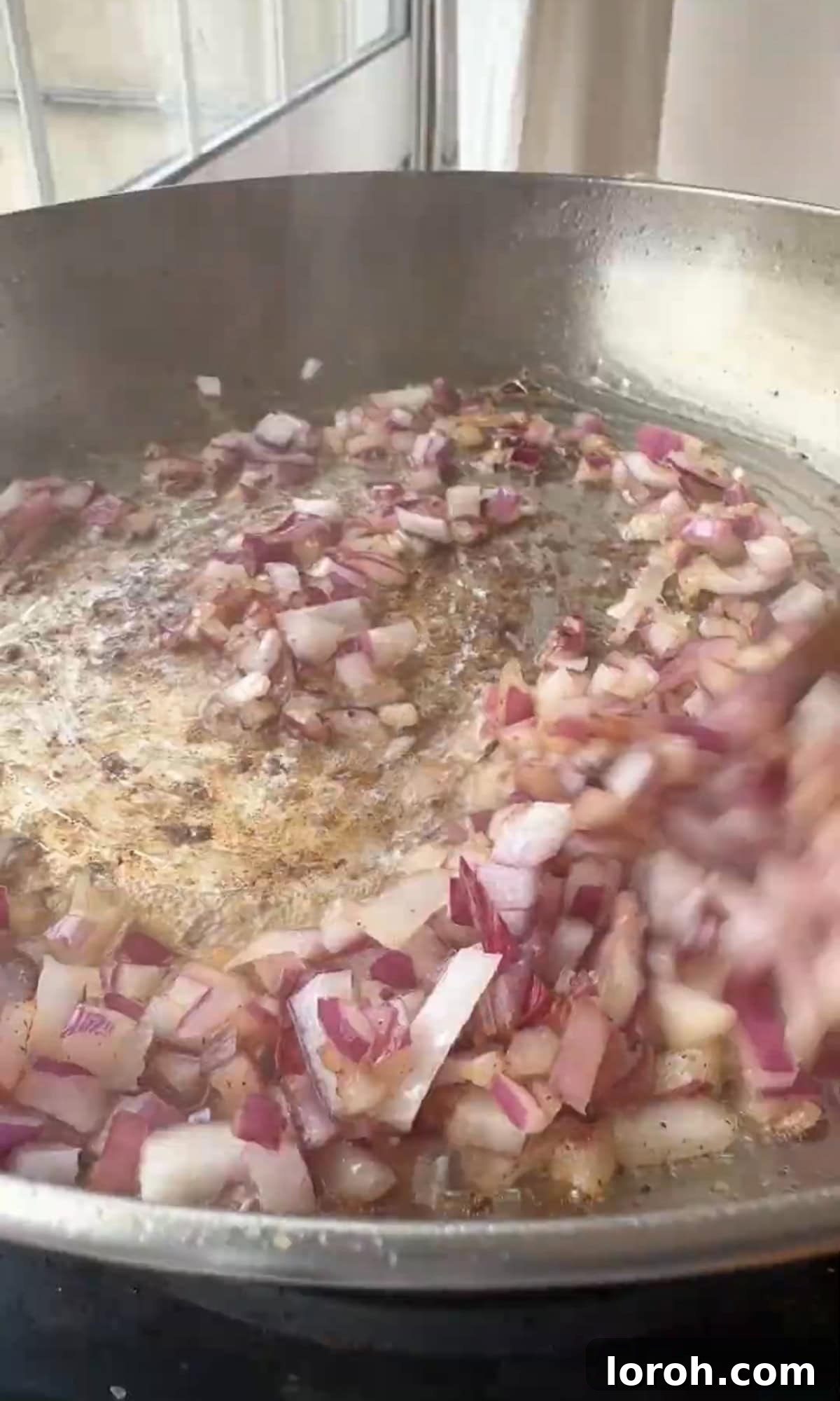 Finely chopped onions and garlic gently sautéing in a pan.