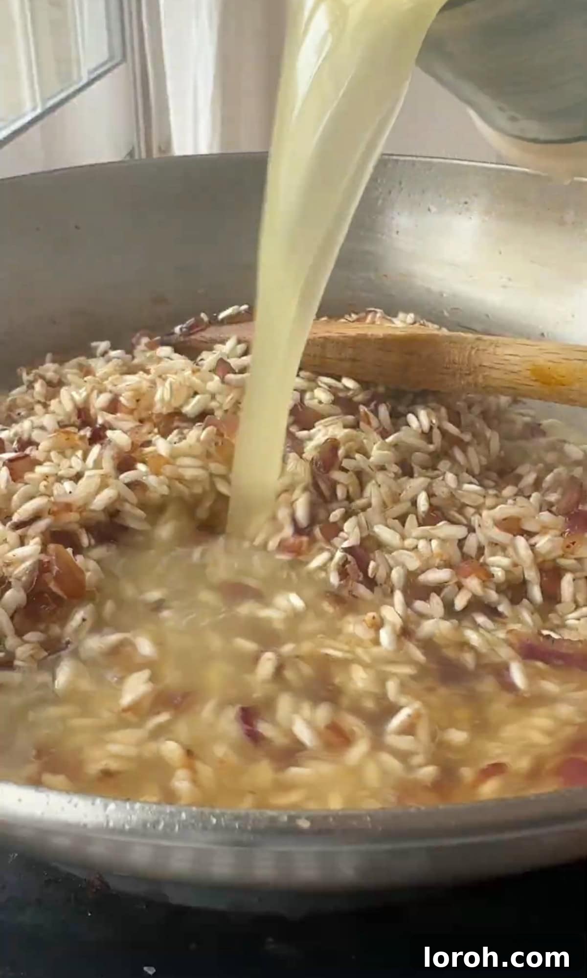 A ladle pouring hot stock into the risotto, with a spoon stirring the mixture.