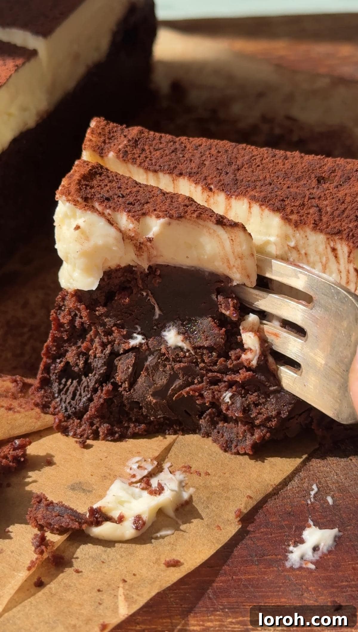 Decadent Cheesecake Brownies 12 Fork cutting through a piece of cheesecake brownie, highlighting the textures.