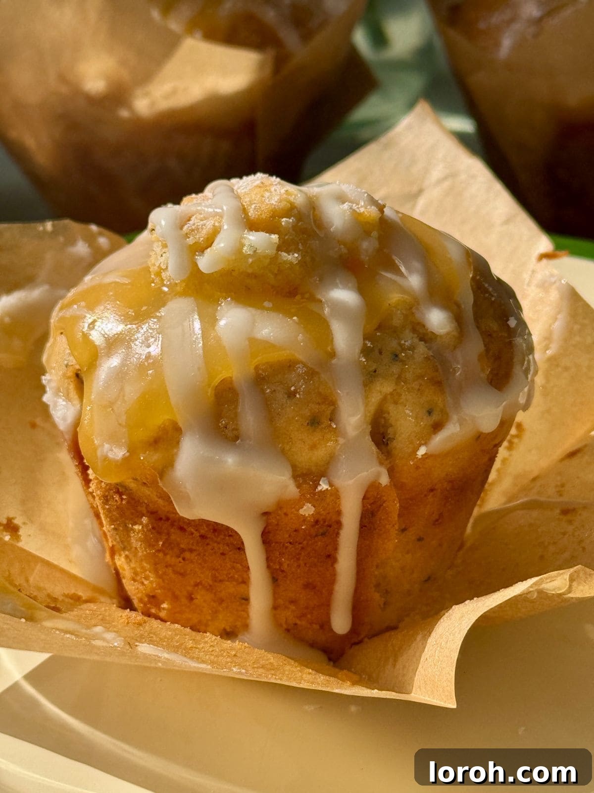 Zesty Lemon Poppy Seed Delights 2 One freshly baked lemon and poppy seed muffin with a hint of lemon glaze, resting on baking paper.