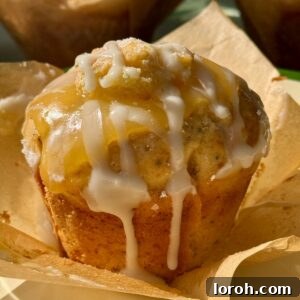 One lemon and poppy seed muffin on baking paper, highlighting its golden exterior and delicate glaze.
