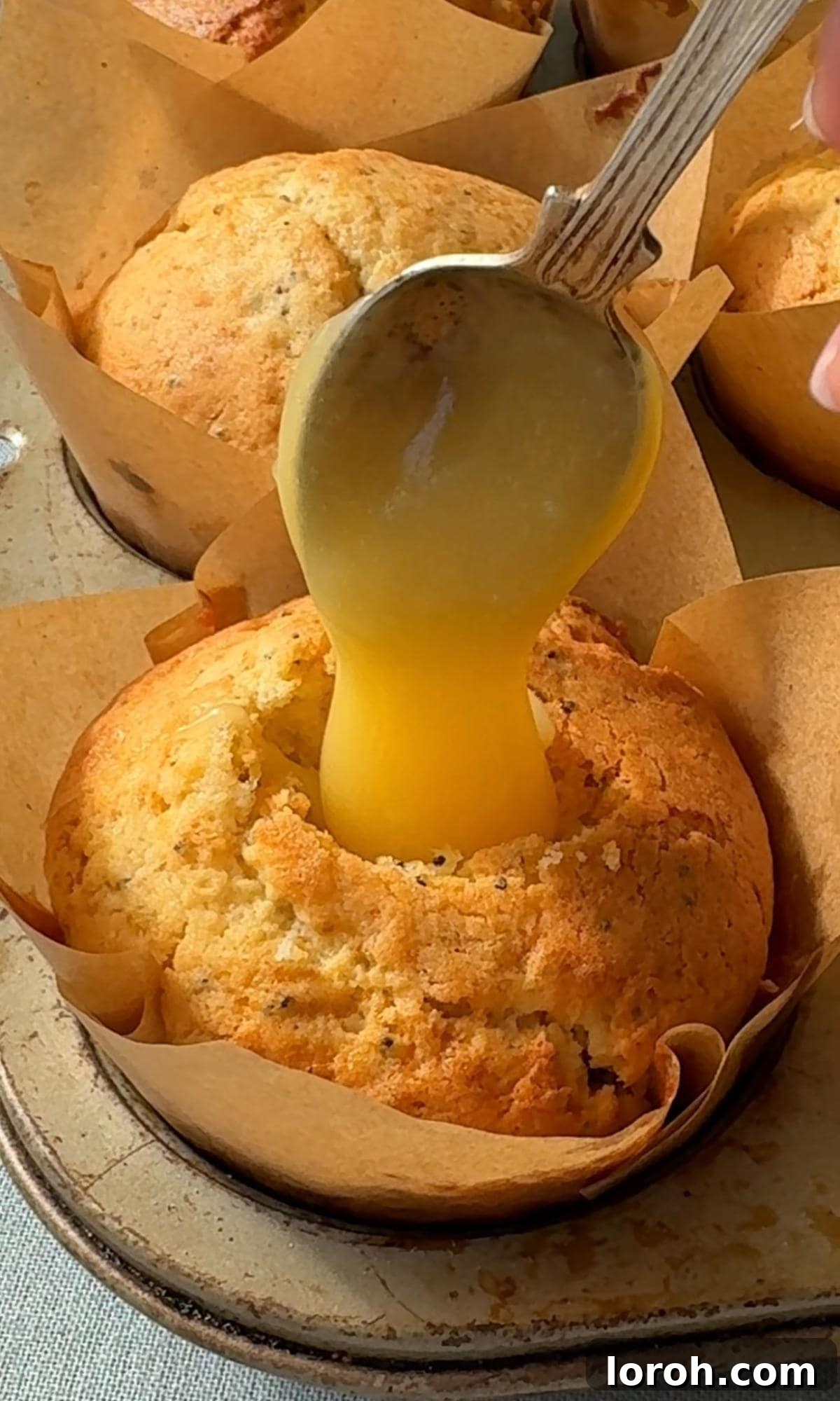 Zesty Lemon Poppy Seed Delights 10 Adding a spoonful of vibrant lemon curd into the hollowed-out center of a lemon muffin.