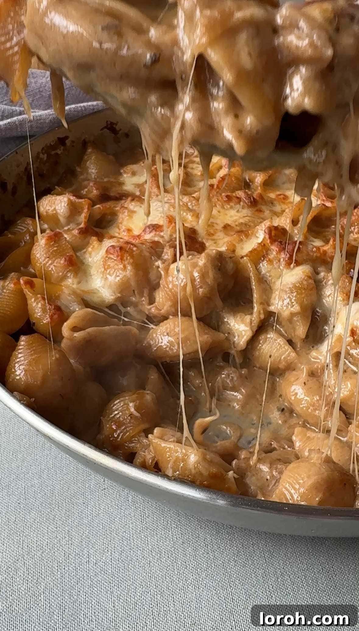 spooning french onion soup pasta. Close up shot of the creamy pasta with melted cheese.