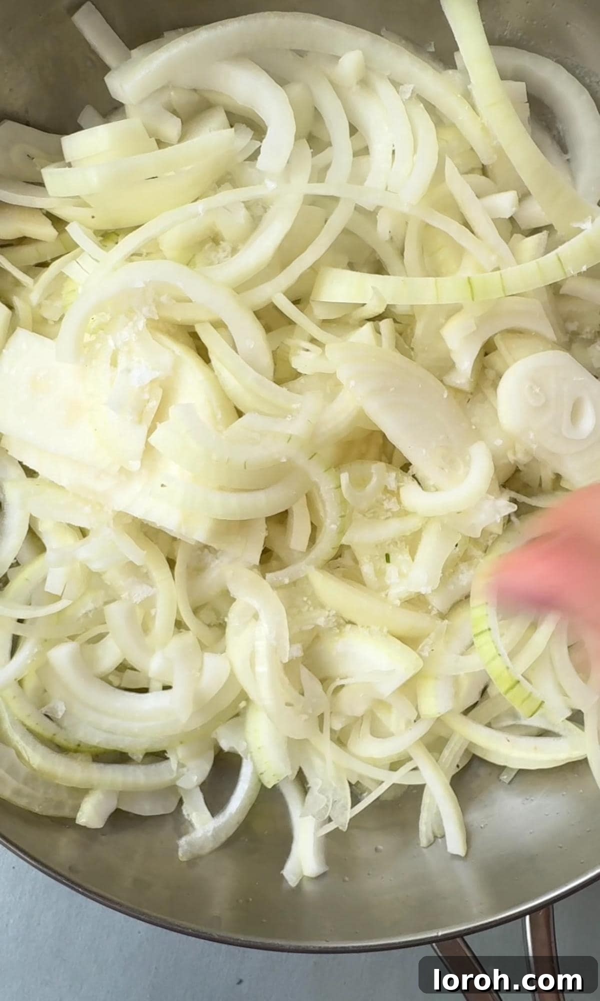 cooking white onions. Sliced white onions gently cooking in a pan with butter and olive oil.