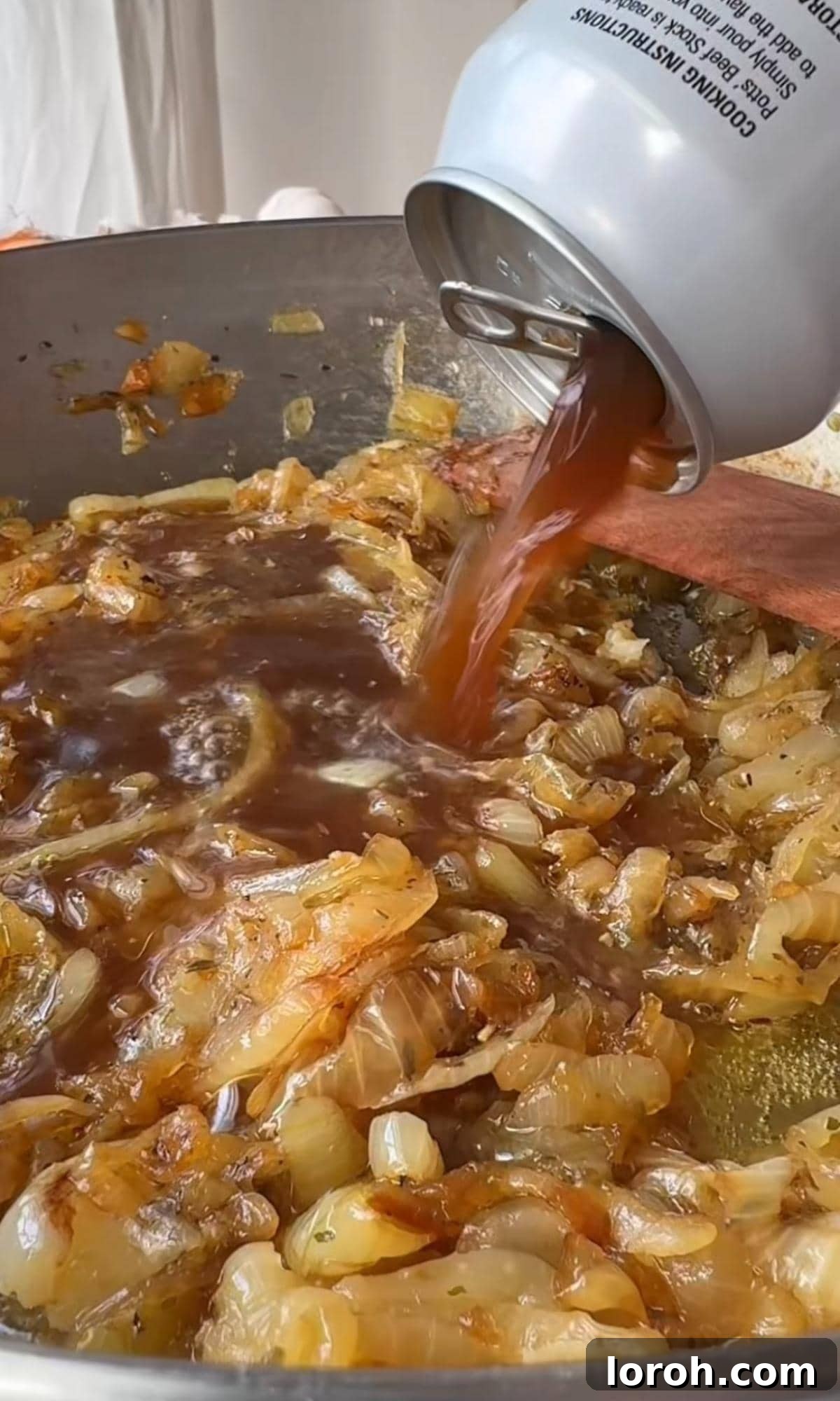adding beef stock to onions. Liquid being poured over caramelized onions and pasta in a pan.