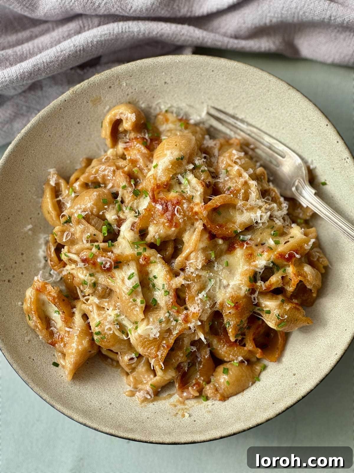 a bowl of french onion soup pasta. A single serving of pasta with a crispy cheese topping, ready to eat.