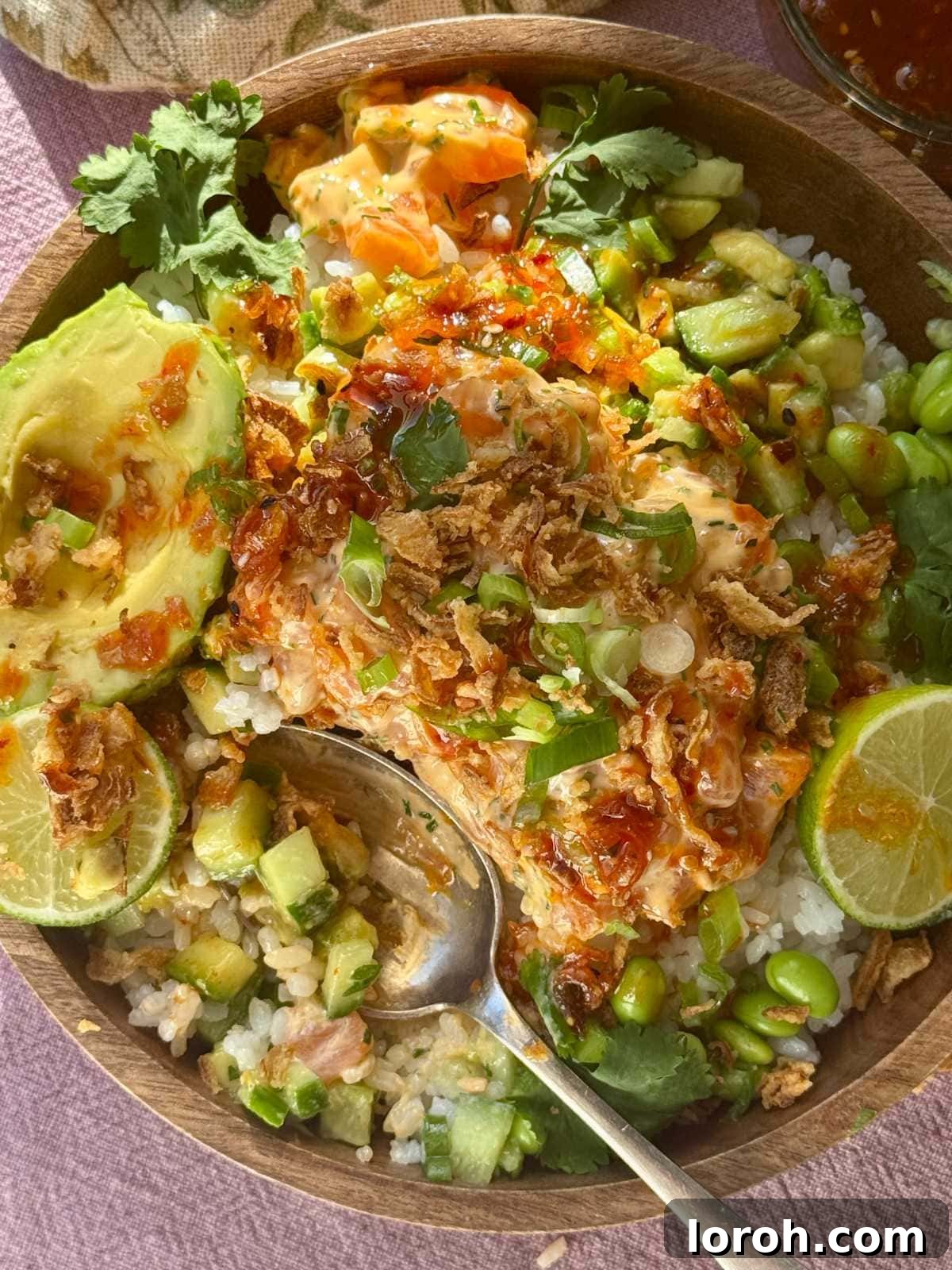 Vibrant salmon sushi bowl with perfectly cooked sushi rice, fresh lime wedges, and crisp spring onions, ready to be enjoyed.