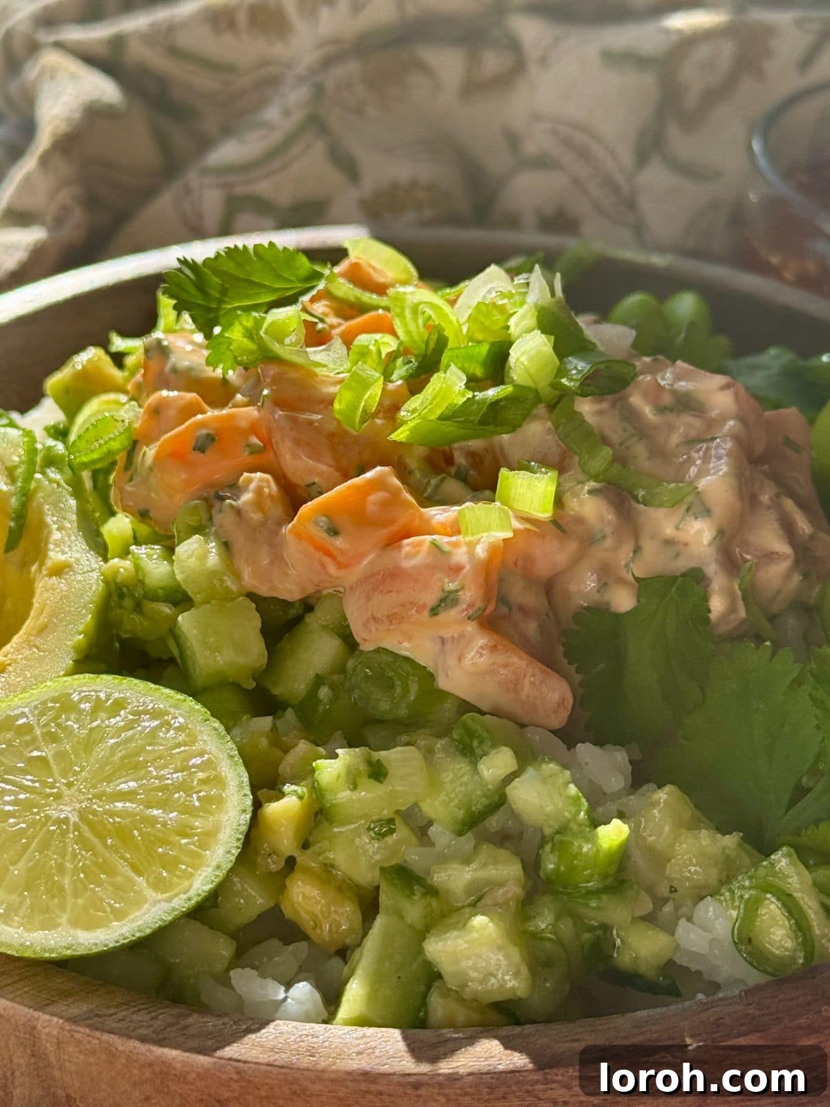 Close-up of fresh ingredients for salmon sushi bowls, including diced sushi-grade salmon, lime, and spring onions.