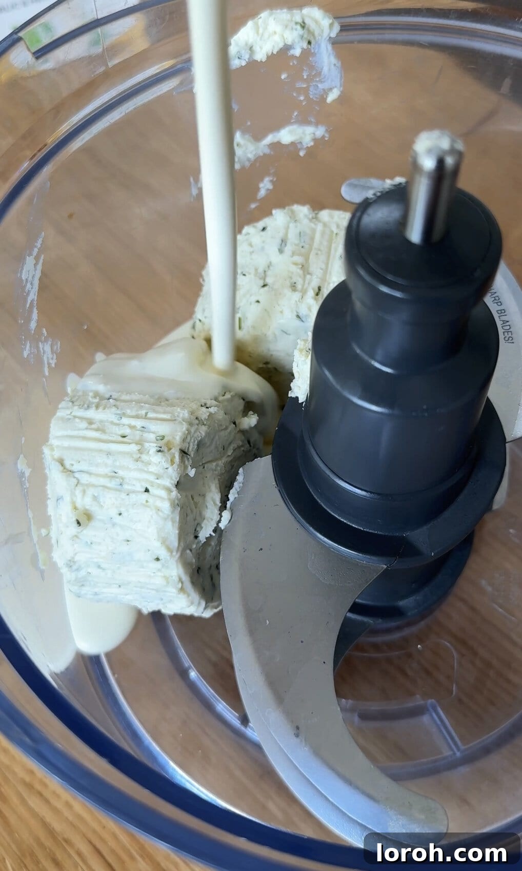 Whipping Boursin cheese with double cream in a food processor to create a smooth, creamy topping.