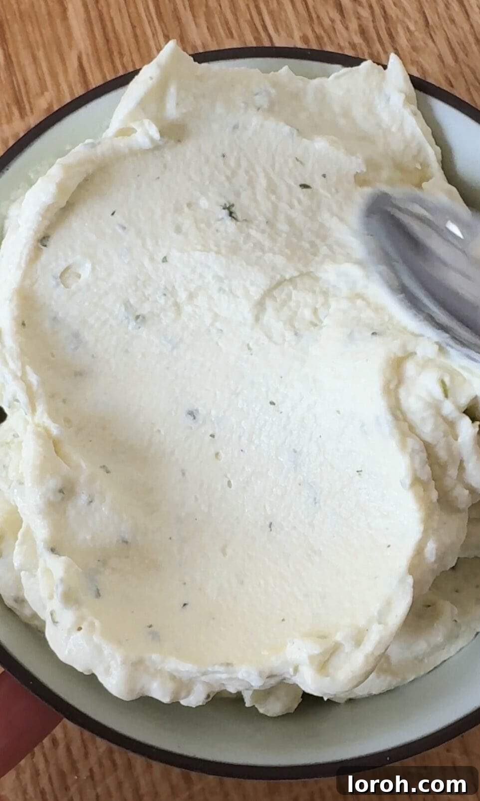 The smooth and creamy texture of freshly whipped Boursin, ready to be dolloped onto the baked gratin.