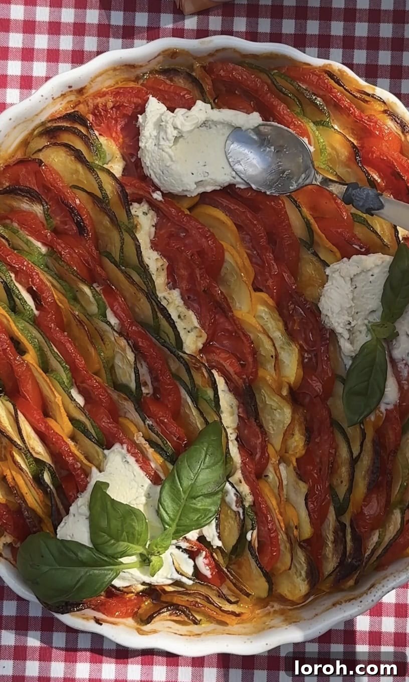 Garnishing the warm zucchini al forno gratin with dollops of whipped Boursin, fresh basil, and a drizzle of vibrant pesto.