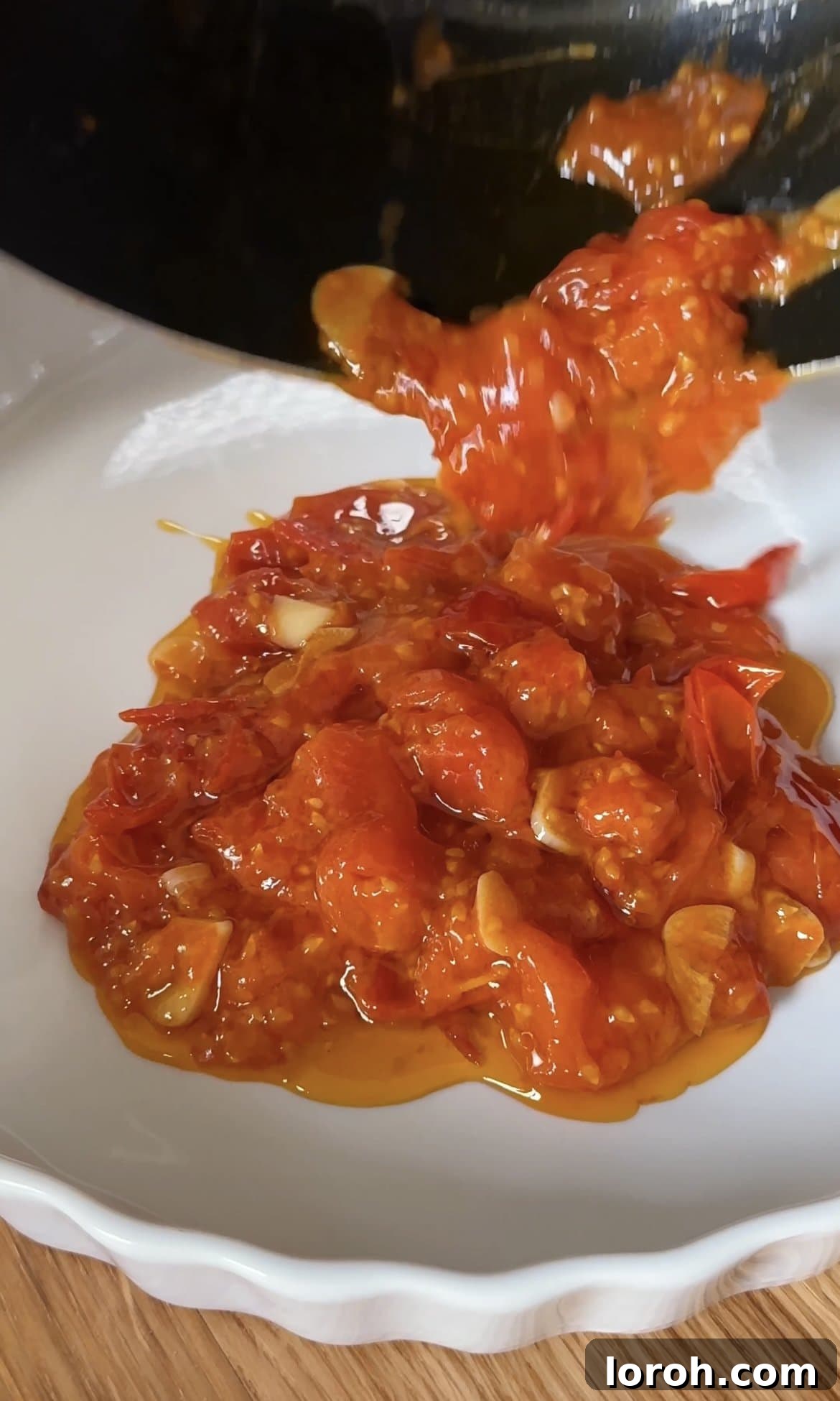 Spreading homemade cherry tomato sauce as the base layer in an oven-safe dish for the gratin.