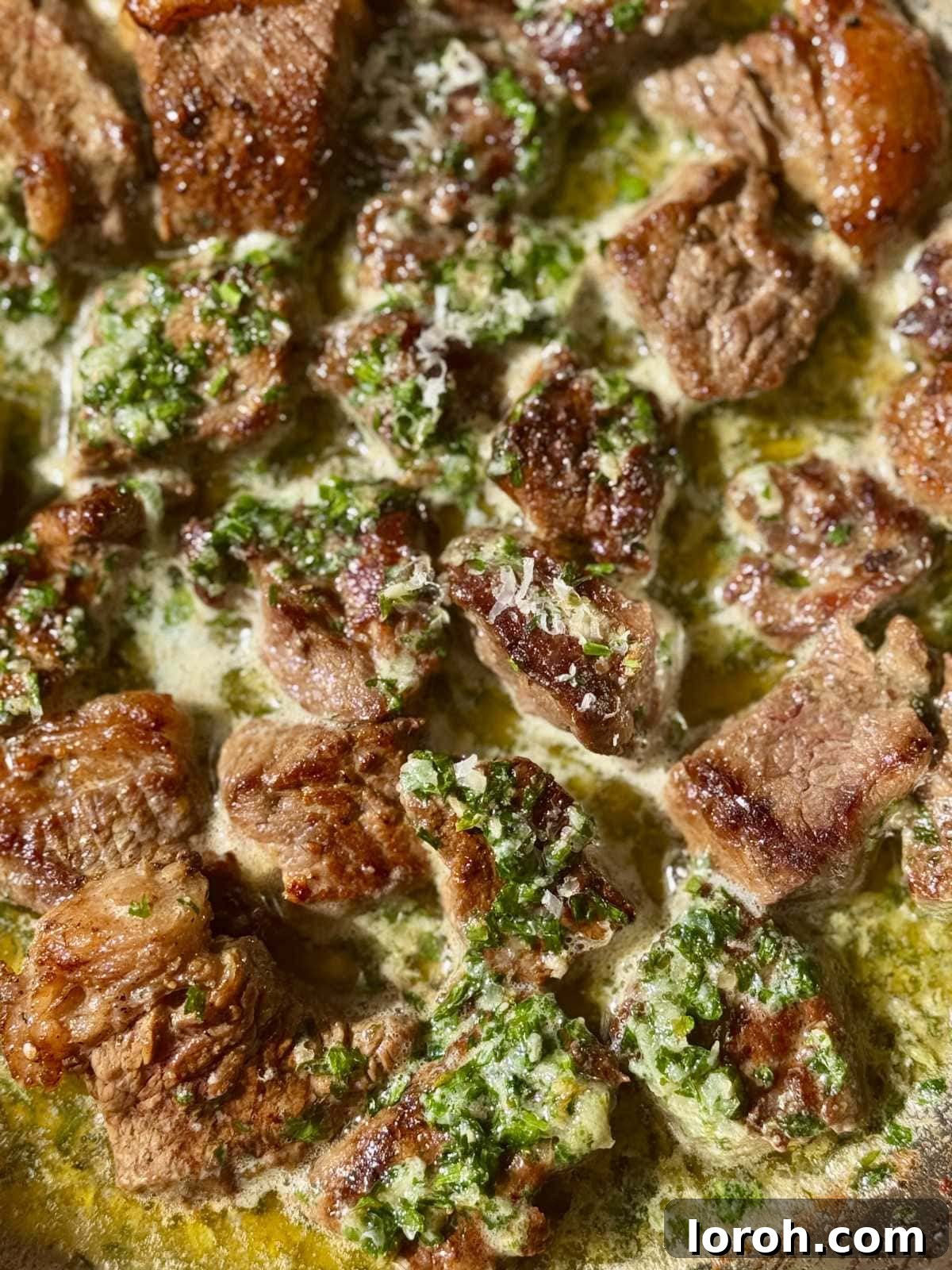Melt-in-Your-Mouth Garlic Butter Steak Bites 3 A sizzling pan filled with golden garlic steak bites coated in a rich, buttery sauce, ready to be served.
