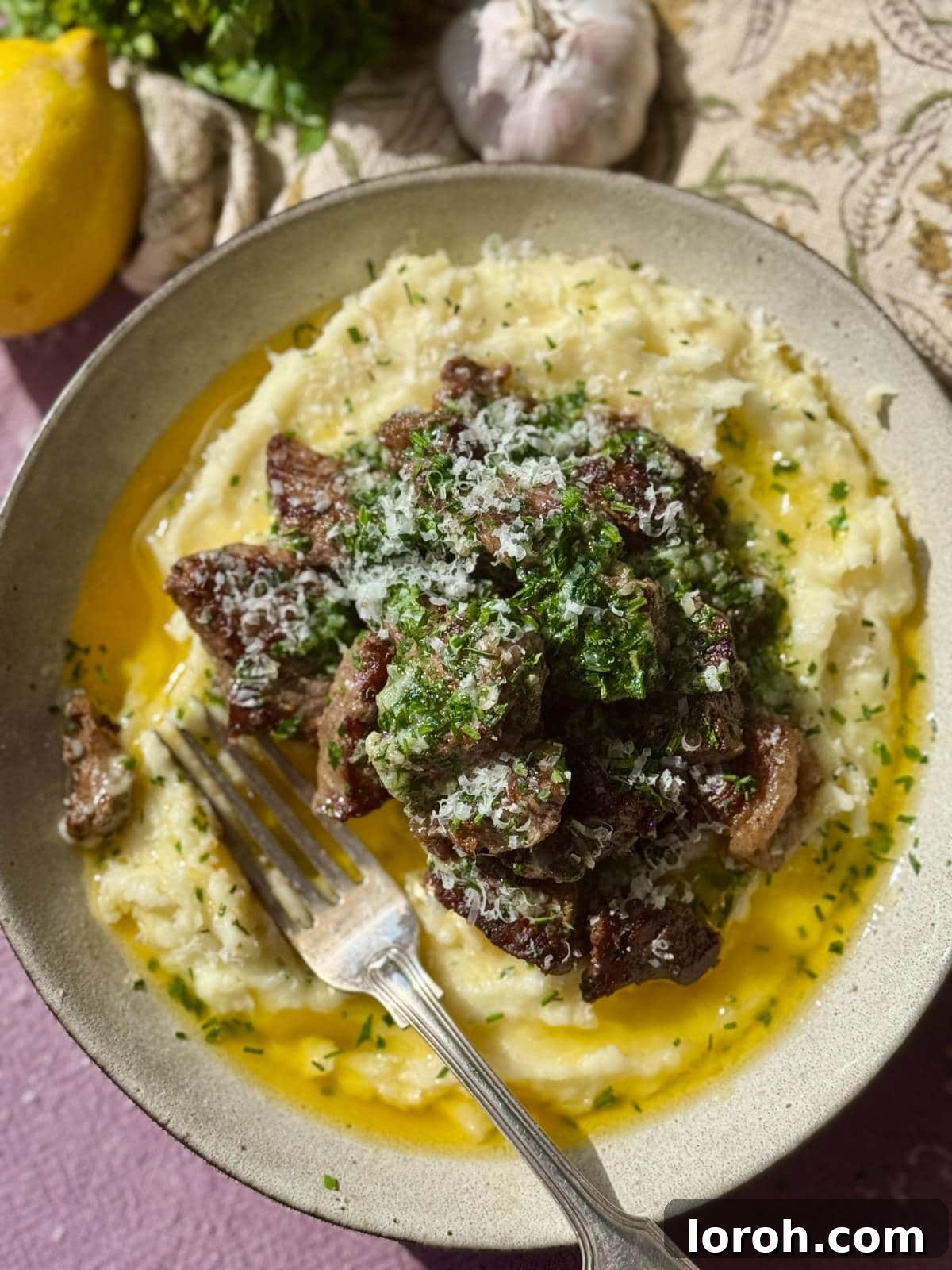 Melt-in-Your-Mouth Garlic Butter Steak Bites 8 Perfectly cooked garlic steak bites arranged beautifully on a bed of creamy mashed potatoes.