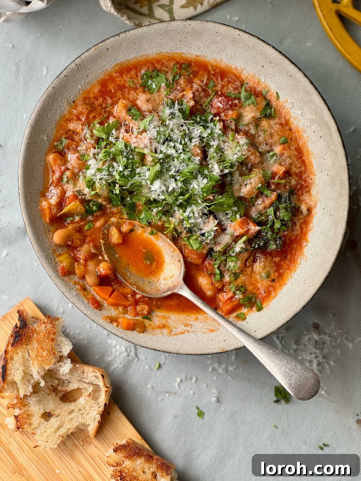 Rustic Tomato and Bean Stew with Cavolo Nero 2 A rustic bowl of hearty tomato bean stew with cavolo nero, served alongside crusty bread, inviting a warm and comforting dining experience.
