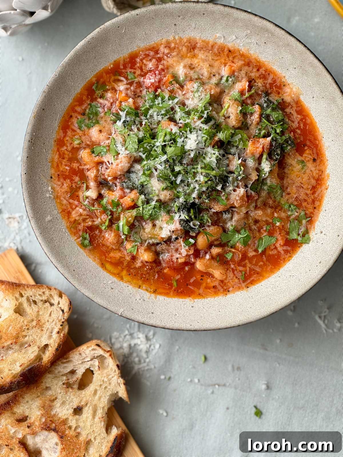 Rustic Tomato and Bean Stew with Cavolo Nero 3 A close-up shot of the rich, thick bean stew in a bowl, garnished with fresh herbs and served with a slice of crusty bread on the side.