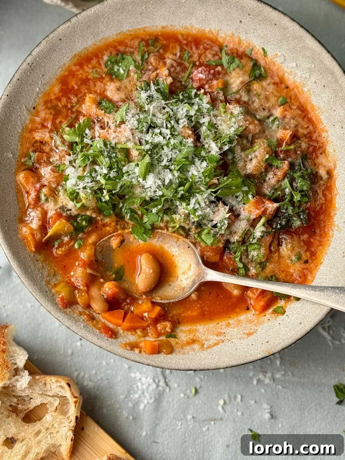 Rustic Tomato and Bean Stew with Cavolo Nero 9 A large serving spoon scooping up a portion of the rich bean stew from a bowl, with crusty bread in the background.