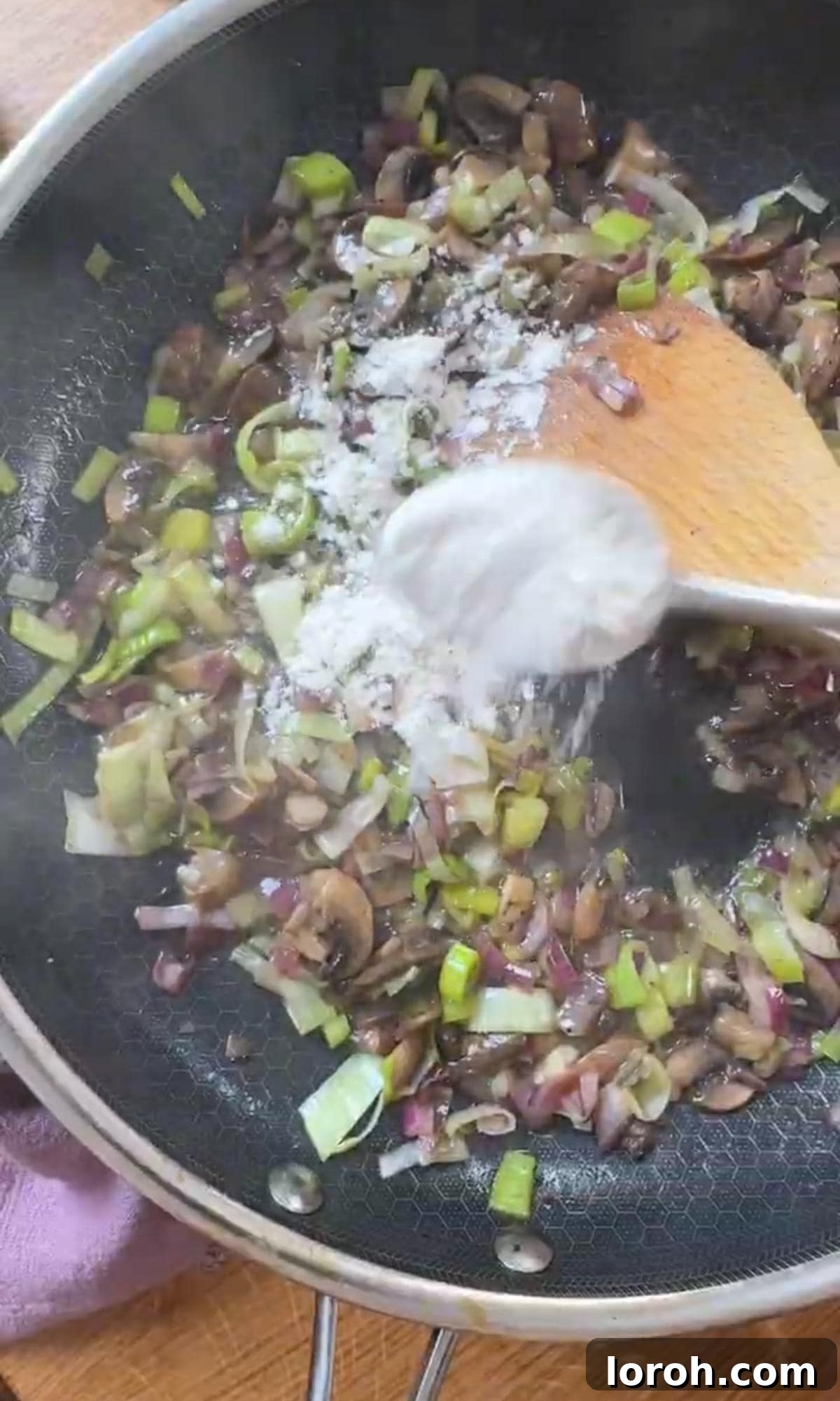 Velvety Chicken, Mushroom, and Leek Pie 5 Adding flour to melted butter and vegetables in a frying pan, creating a roux for the pie filling.