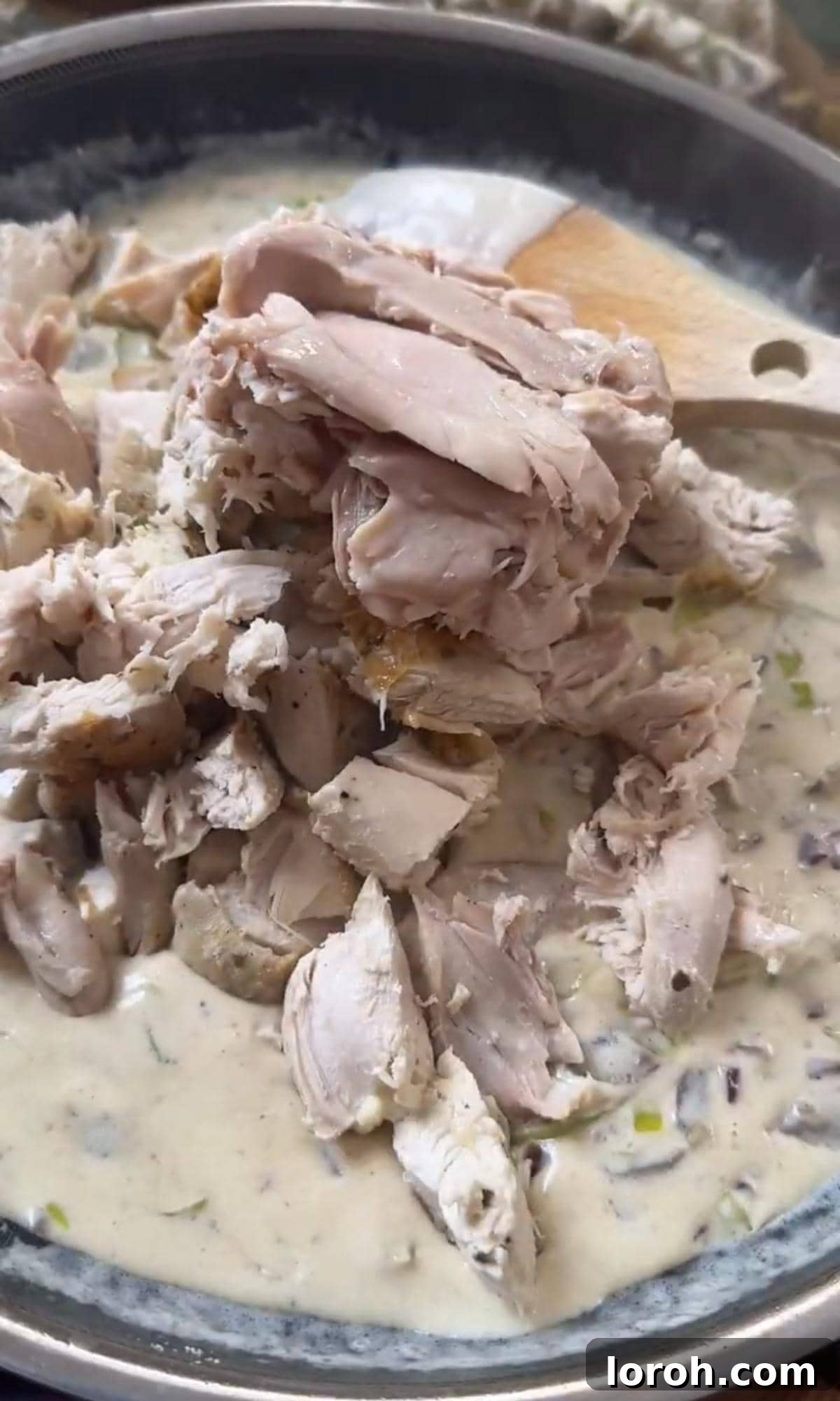 Velvety Chicken, Mushroom, and Leek Pie 7 Adding shredded cooked chicken to the creamy, thickened pie filling in a frying pan, ready for mixing.