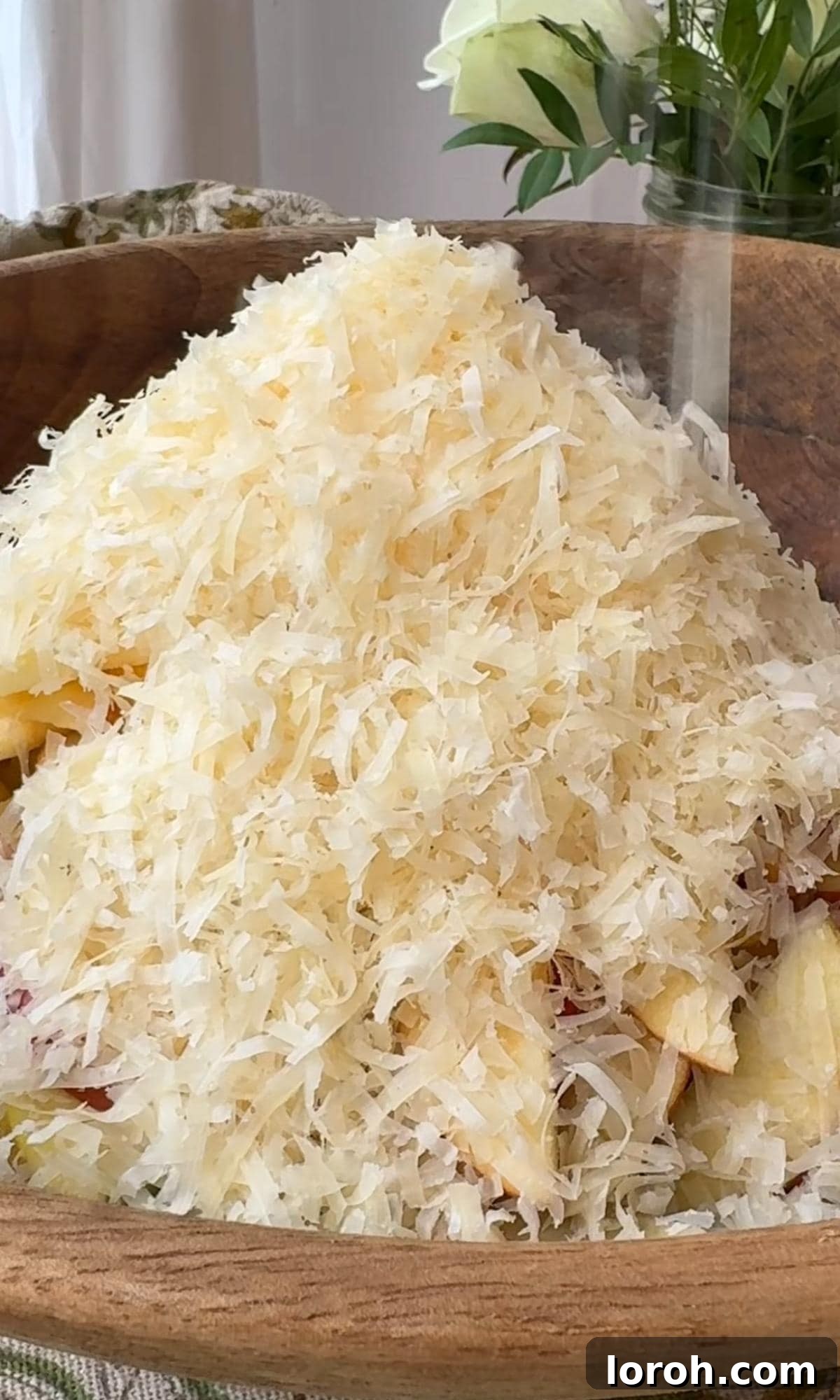 Grated Manchego cheese being added to the salad mixture in a bowl.