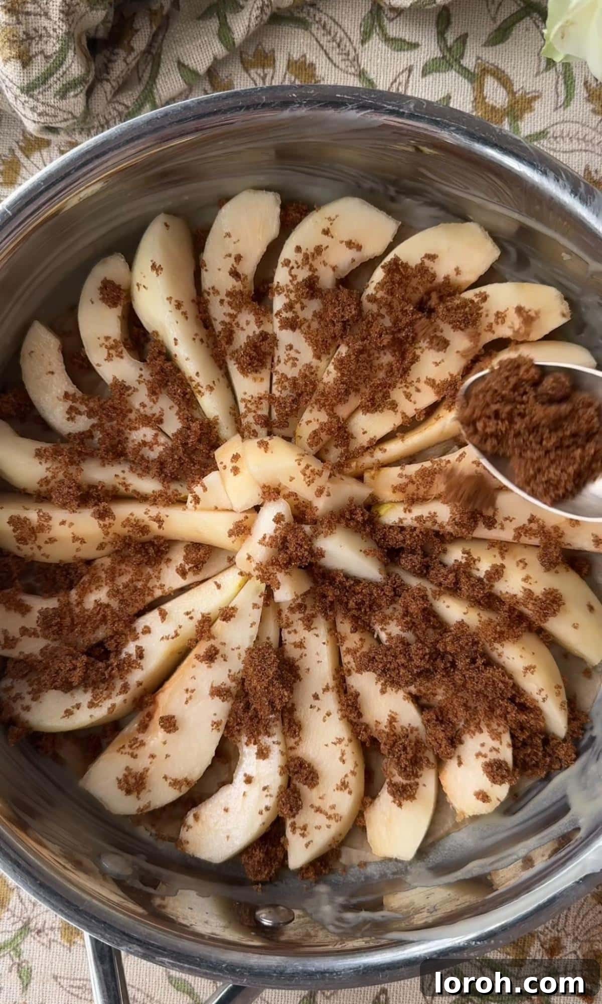 Golden Pear Flip Cake with Decadent Fudge Drizzle 6 Dark brown sugar being evenly sprinkled over the arranged pear slices in the cake tin, ready for baking.