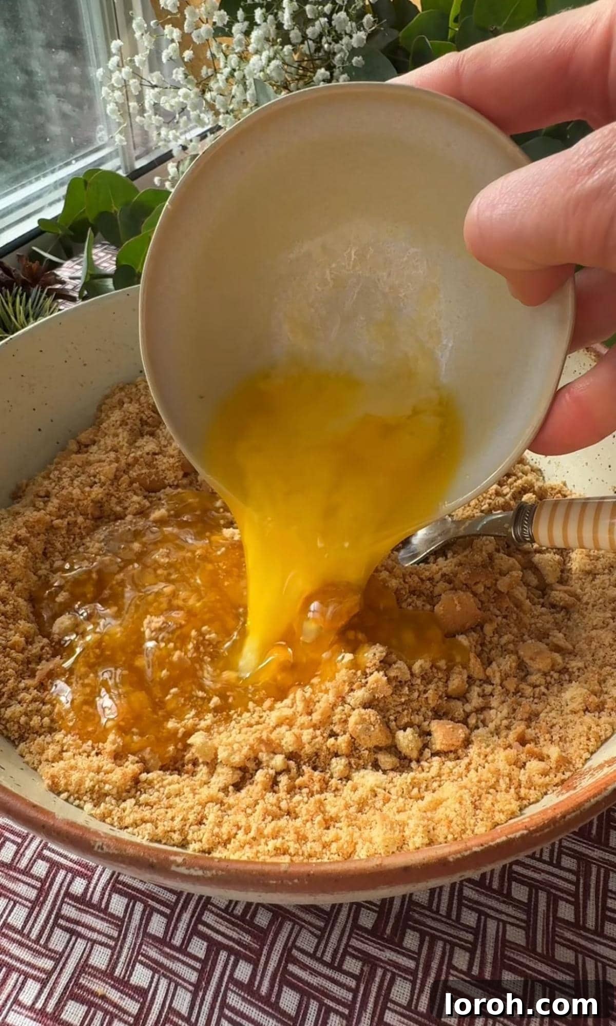 Effortless Christmas Cheesecake Bites 4 pouring melted butter into the biscuit crumb.