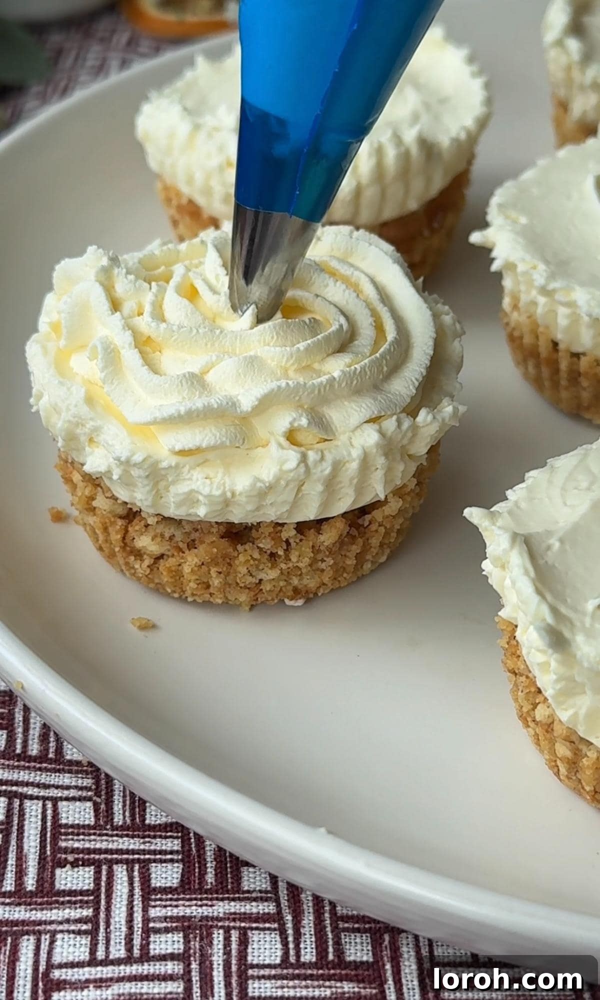 Effortless Christmas Cheesecake Bites 10 piping cream onto christmas cheesecakes.
