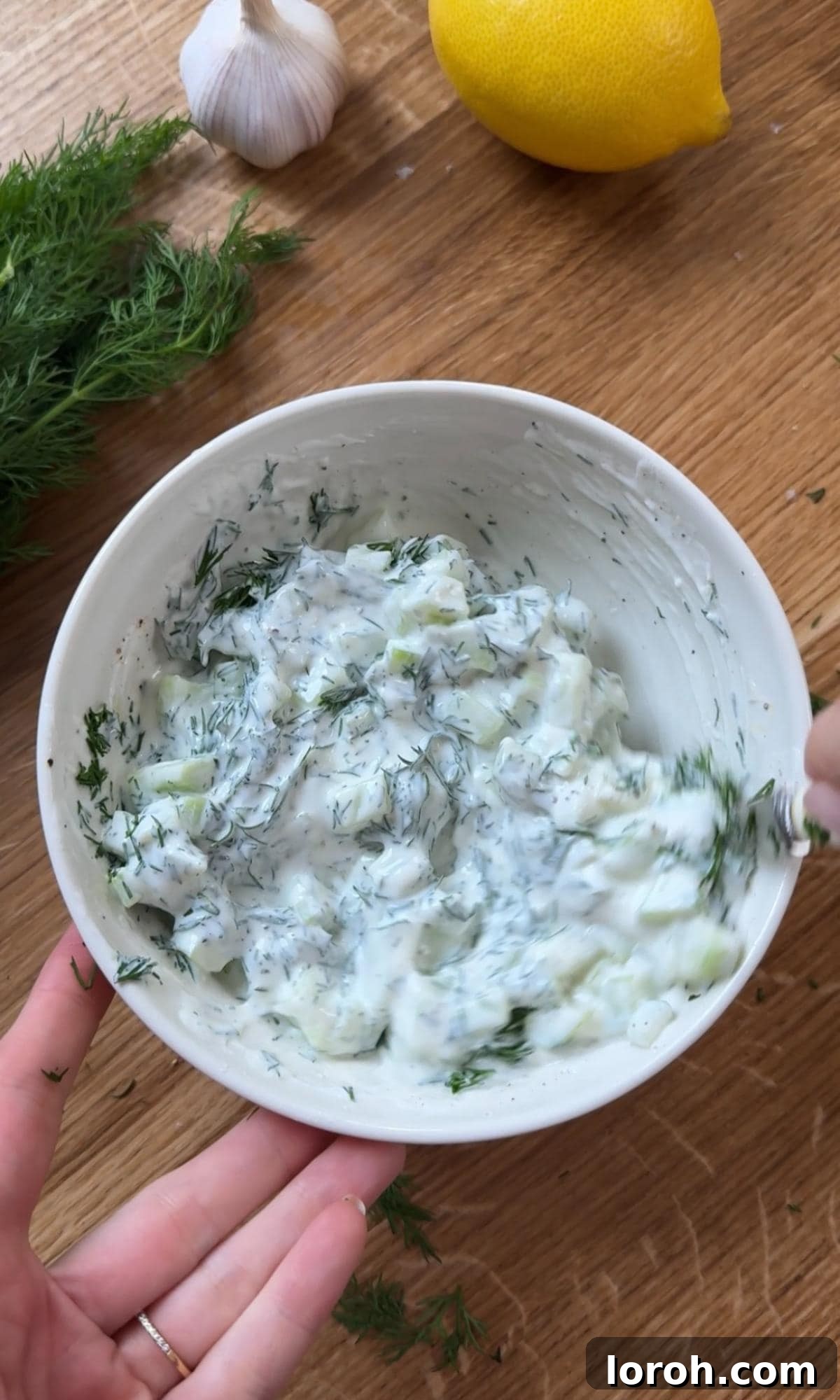 Preparing the refreshing cucumber yogurt sauce in a bowl.