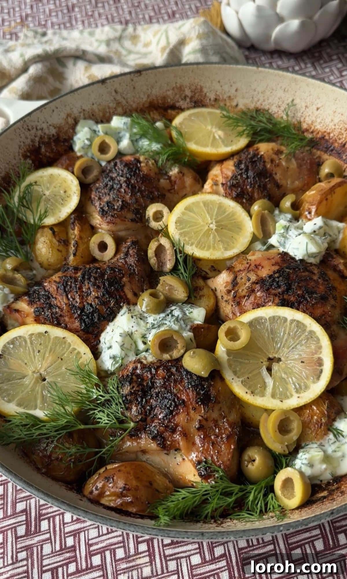 Garnishing the roasted Greek chicken and lemon potatoes with fresh lemon slices and dill.