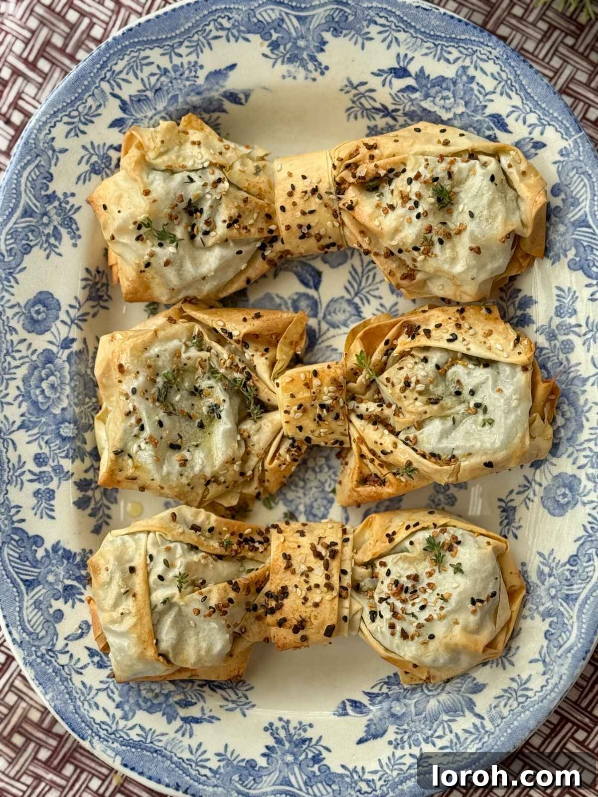 Close-up of golden brown spinach feta filo bows on a blue plate, highlighting their crispy texture.