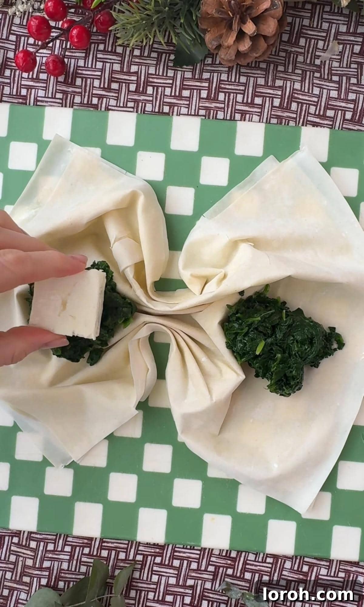 Spinach and feta mixture being spooned onto filo pastry, preparing for folding.