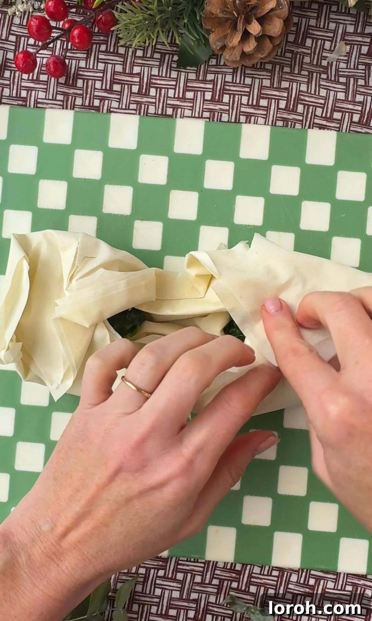 Filo pastry being folded upwards to meet in the center, forming the bow shape around the filling.