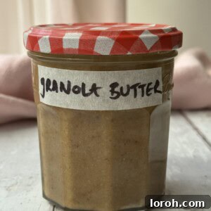 A charming jar of homemade granola butter, sealed with a gingham lid and labeled, ready to be enjoyed.