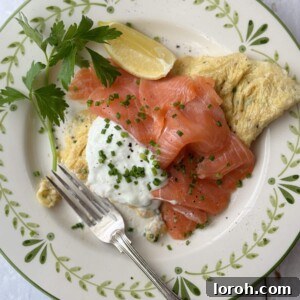 A delicate salmon omelette, perfectly cooked and served on a pristine white plate with a fork.