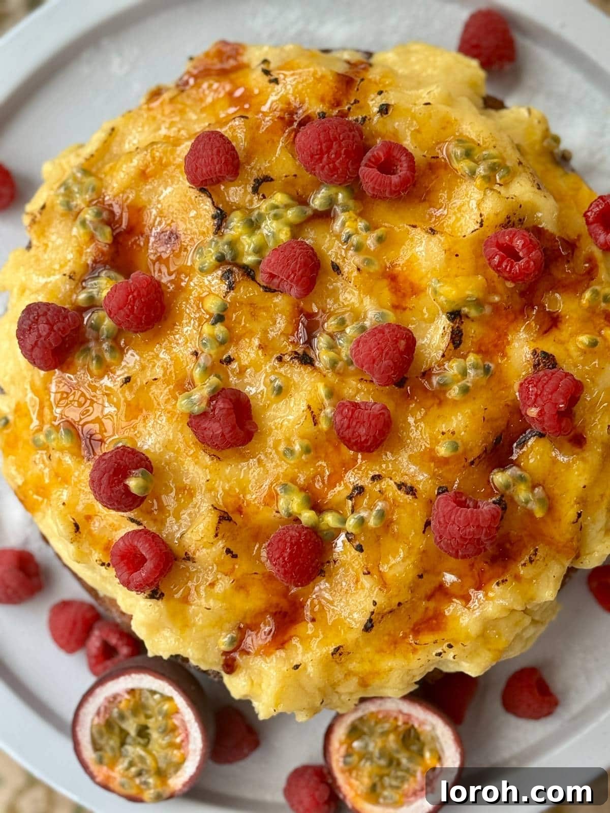 No-Fuss Torched Custard Cake 3 A whole crème brûlée cake beautifully garnished with fresh raspberries and passionfruit pulp.