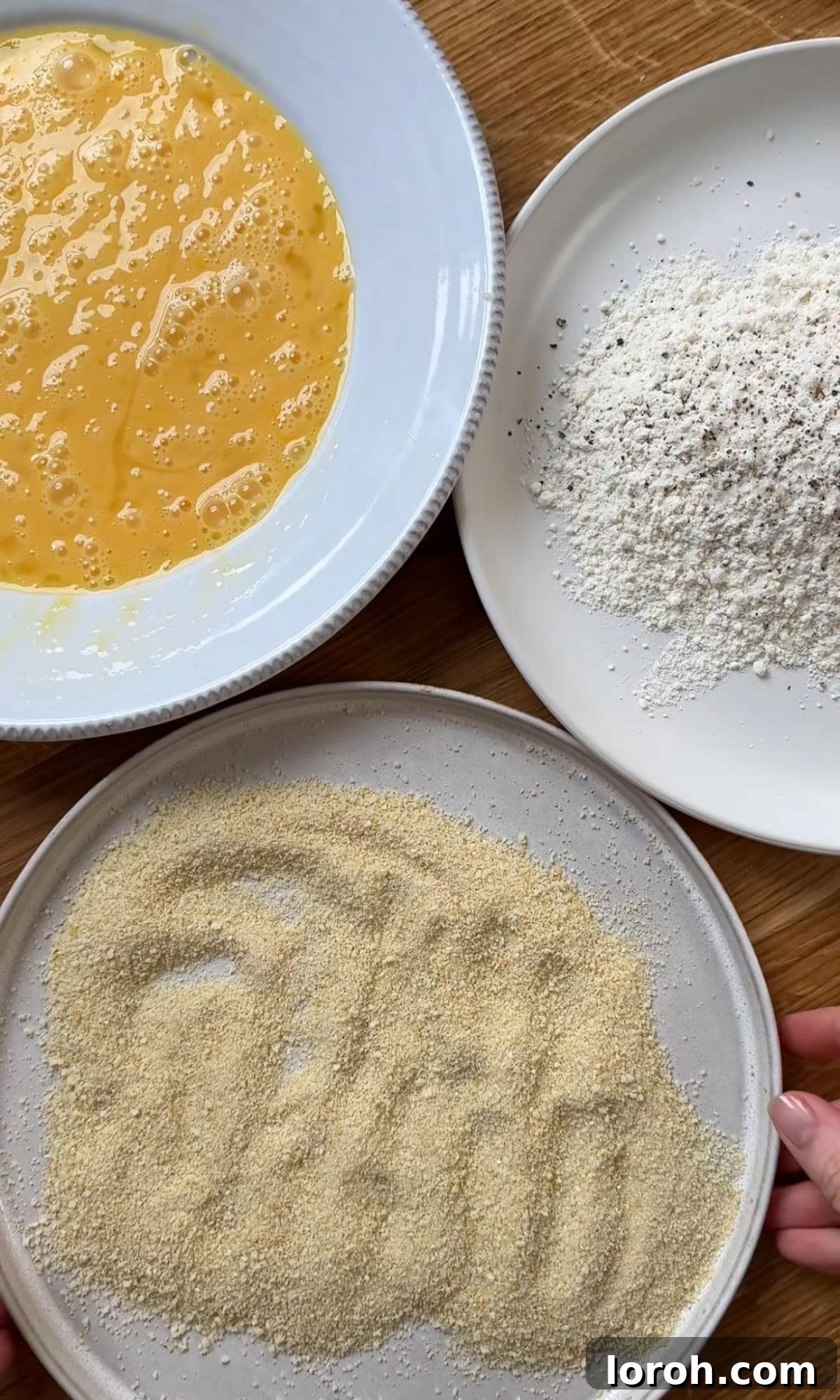 Setting up a traditional three-bowl breading station for deep fried brie with flour, beaten eggs, and panko breadcrumbs.