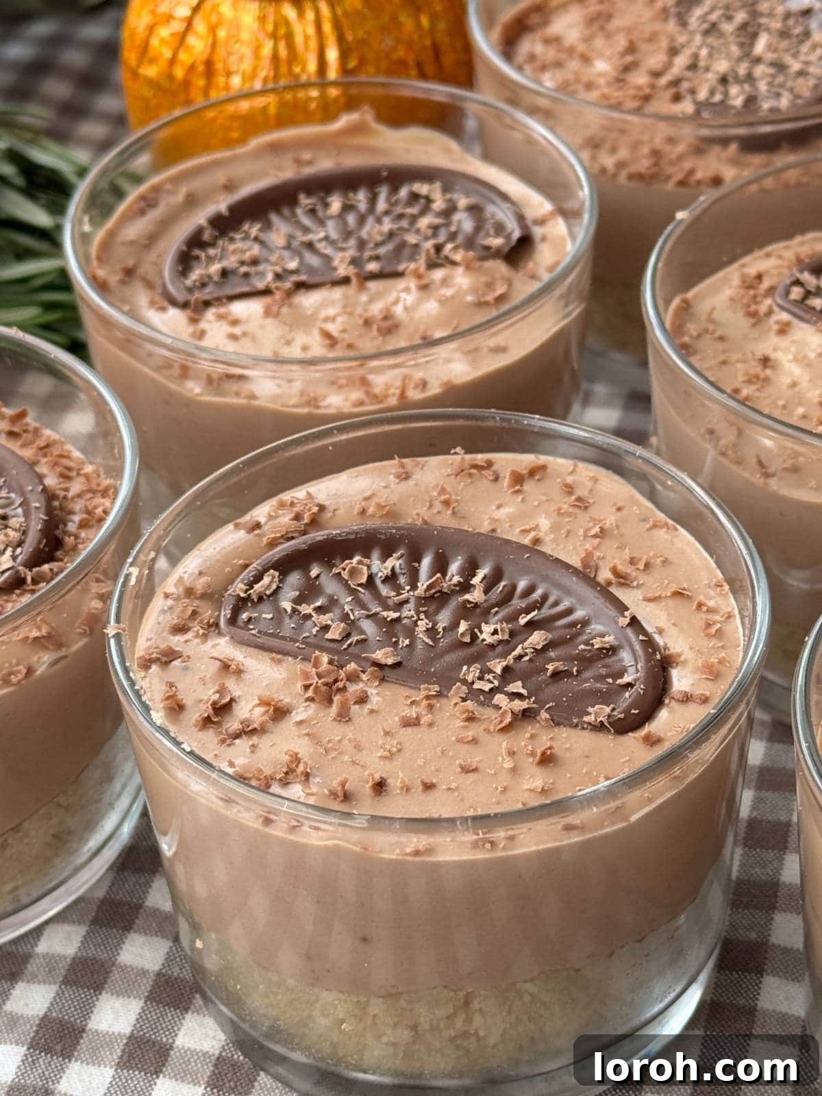 Two individual chocolate orange cheesecakes in small glasses, garnished with Terry's Chocolate Orange segments and grated chocolate.