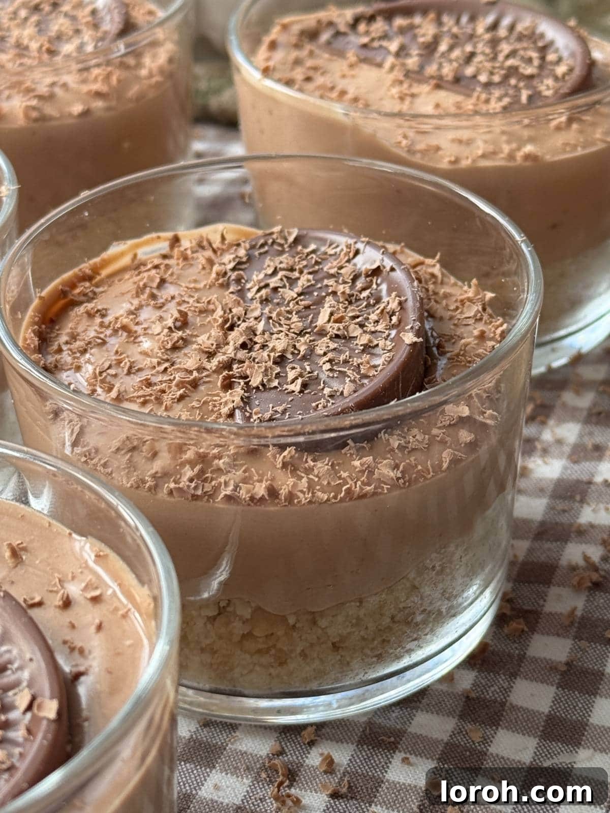 Close-up of a chocolate orange cheesecake pot, showing layers of biscuit base and creamy filling, garnished with a chocolate orange segment.