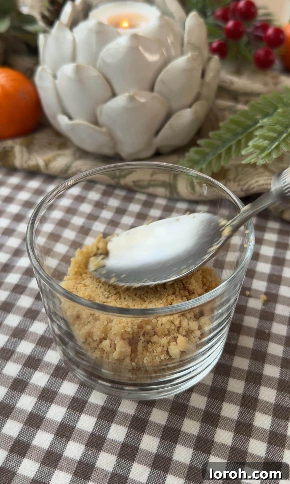 Pressing a biscuit base firmly into a small glass pot.