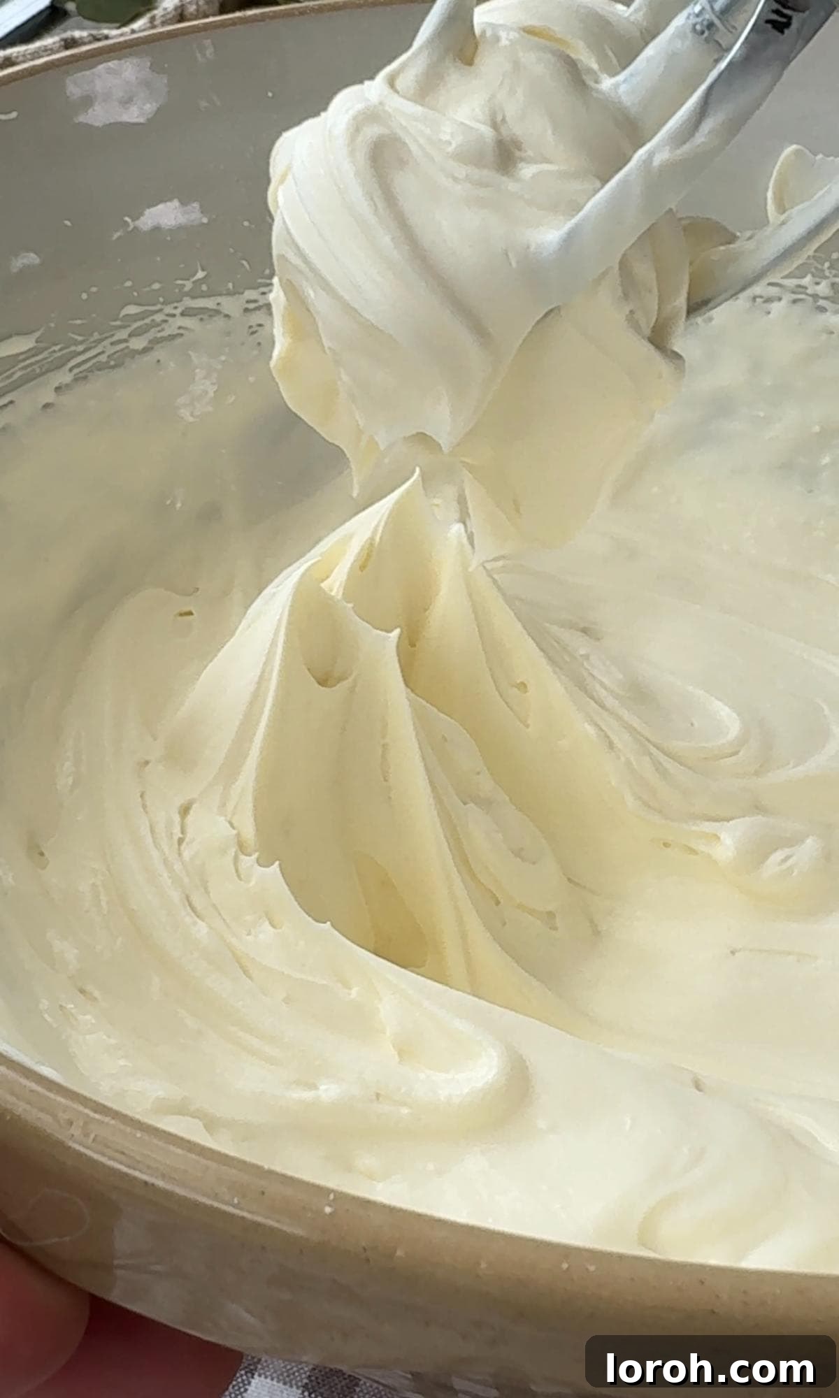 Whisking double cream, cream cheese, and icing sugar together until smooth.