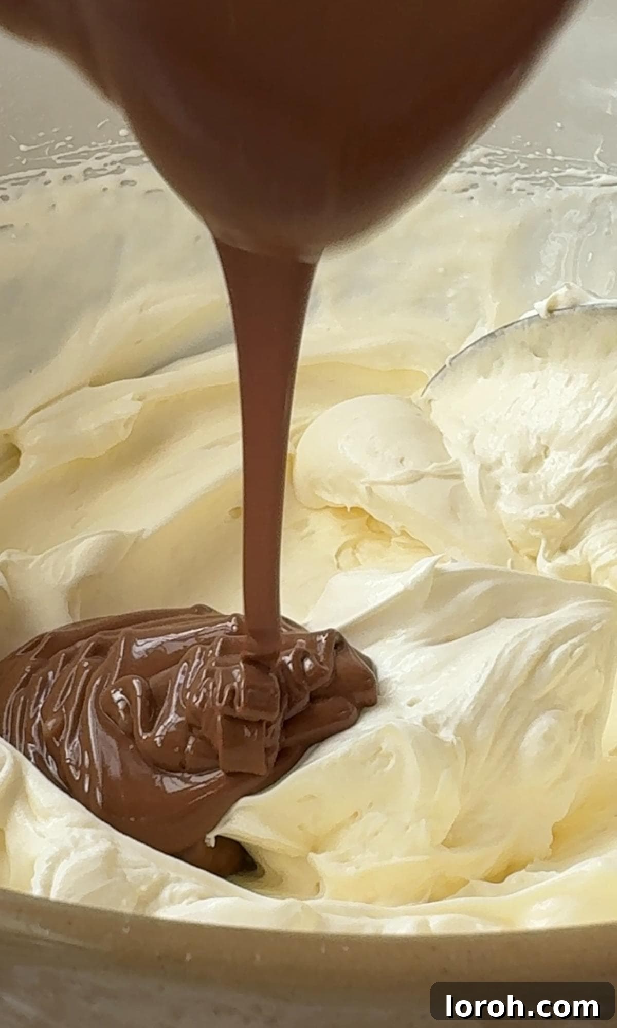 Pouring slightly cooled melted chocolate into the cheesecake mixture.