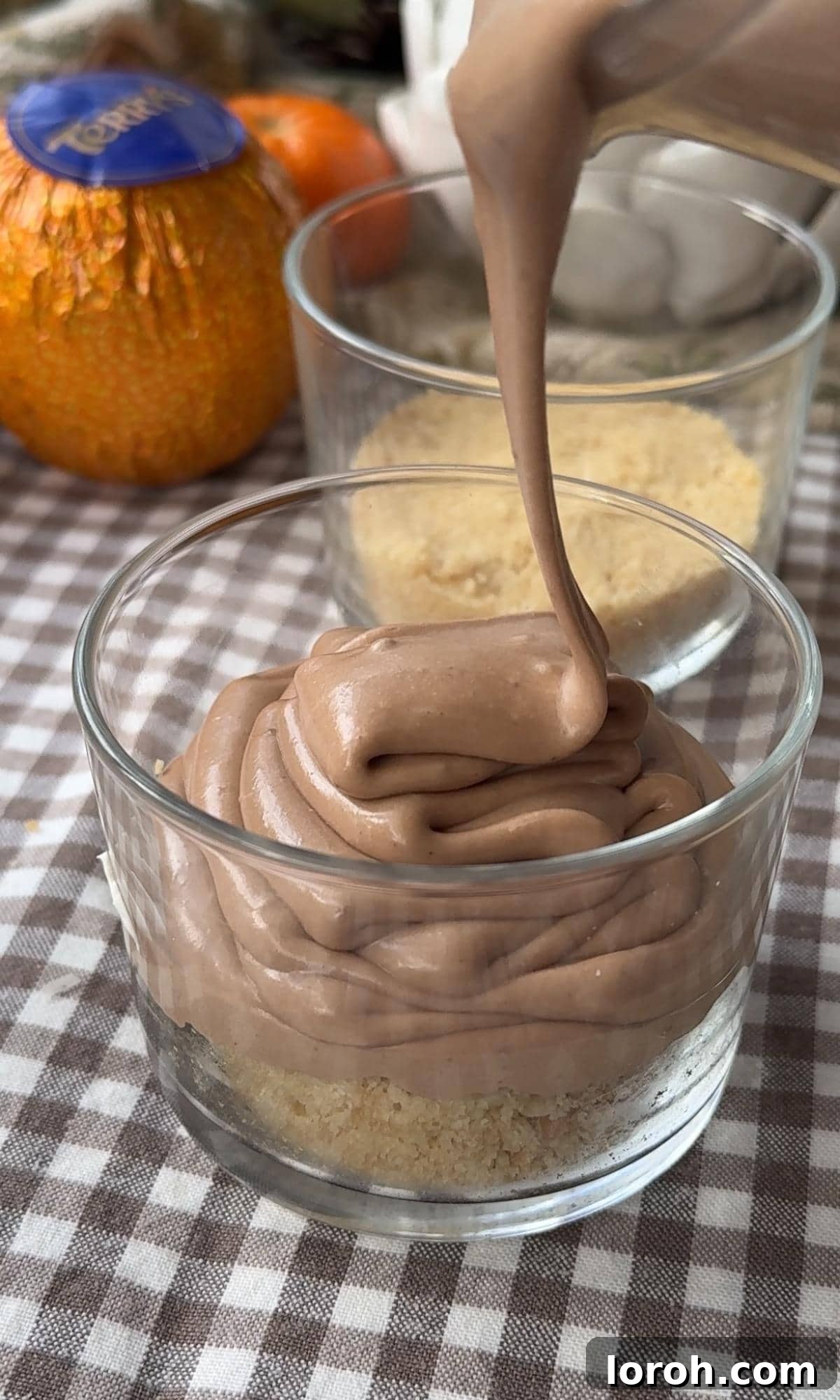 Filling the chocolate orange cheesecake pots with the mixture.