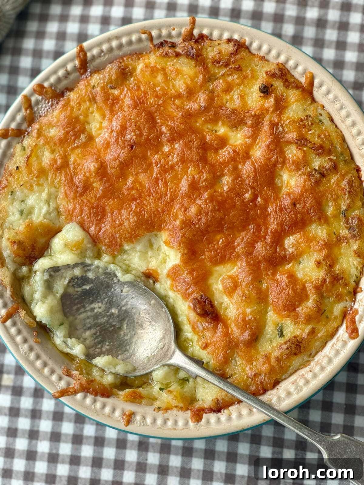 Golden brown twice baked mashed potatoes in a baking dish, with melted cheese and a fork mark surface.