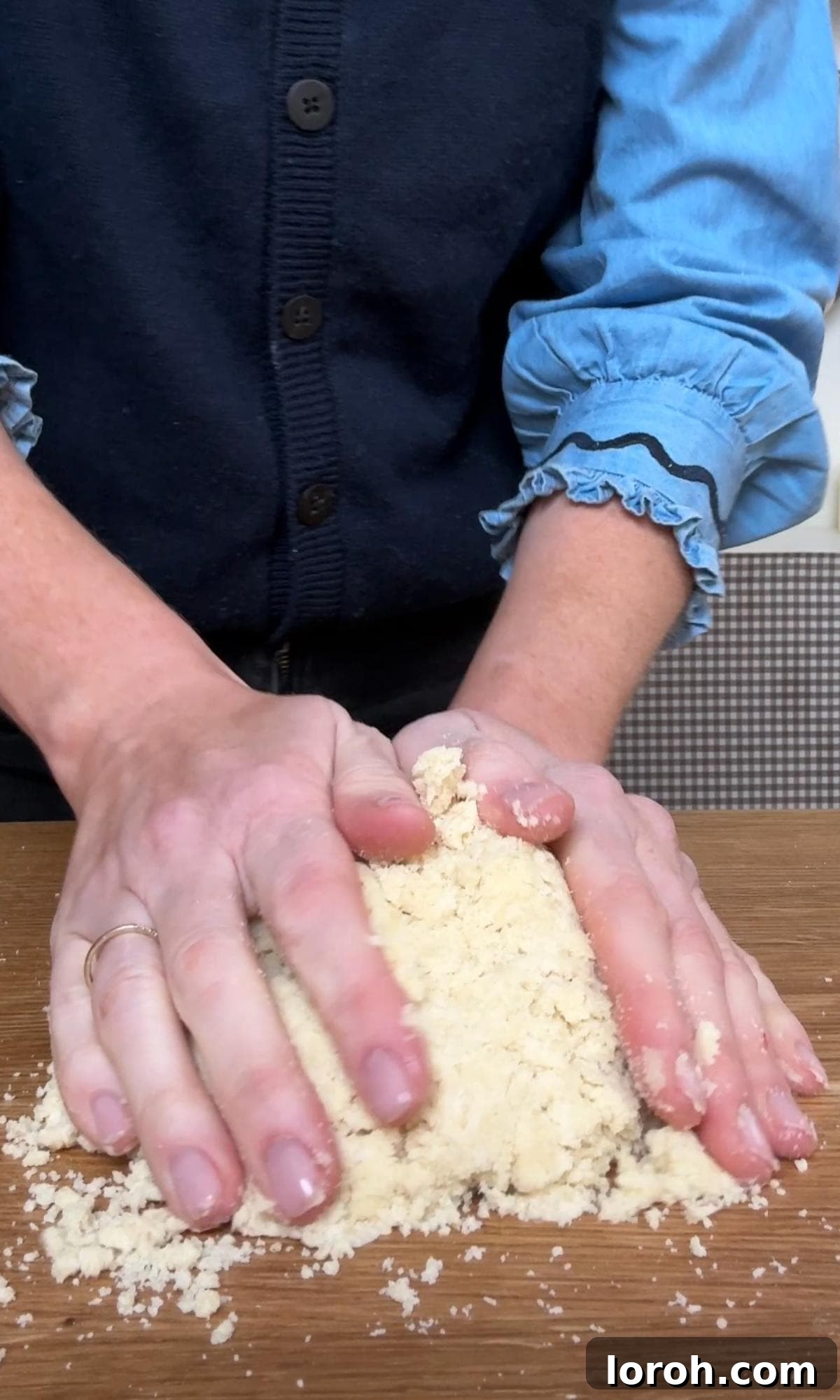 bringing the shortbread dough together with hands on a work surface.