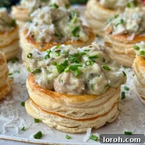 Close-up of golden, flaky chicken and mushroom vol-au-vents on a white plate, showcasing their rich, creamy filling and elegant presentation.