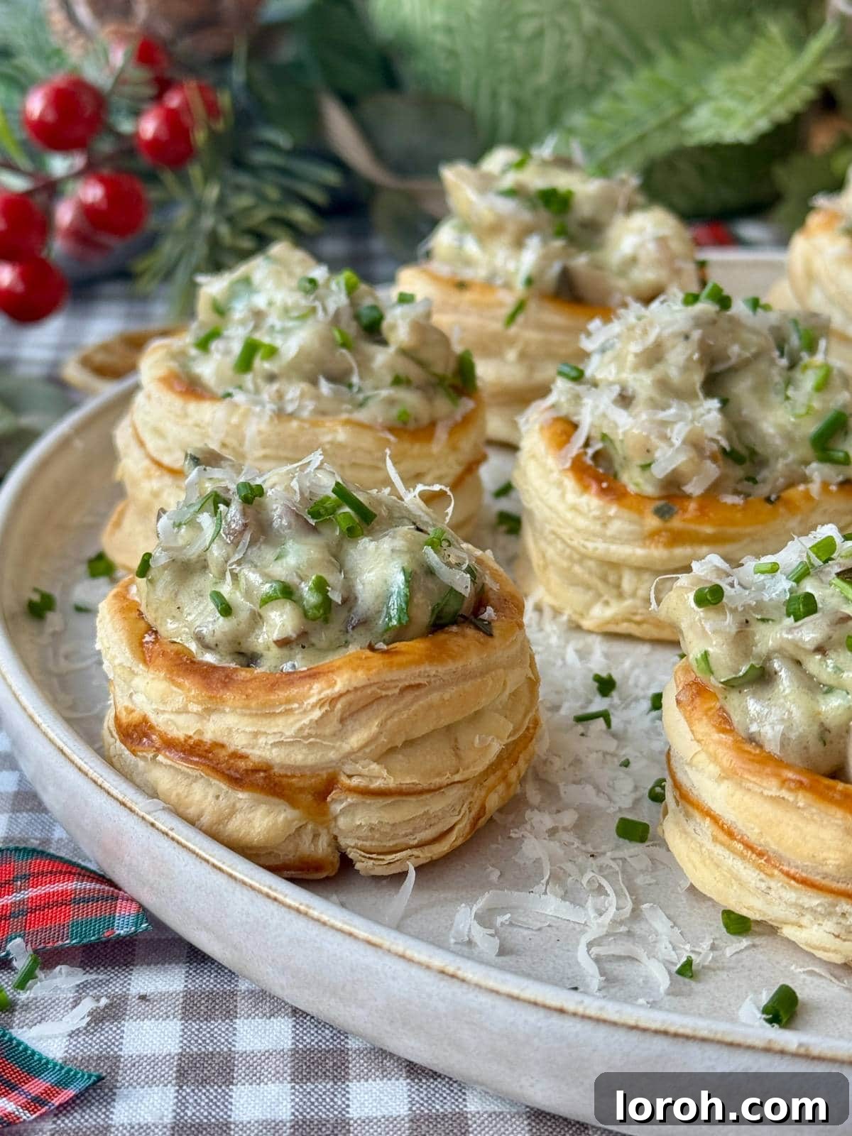 A close-up shot of several golden-brown vol-au-vents, showcasing their perfectly risen puff pastry and flaky texture, presented on a white plate.