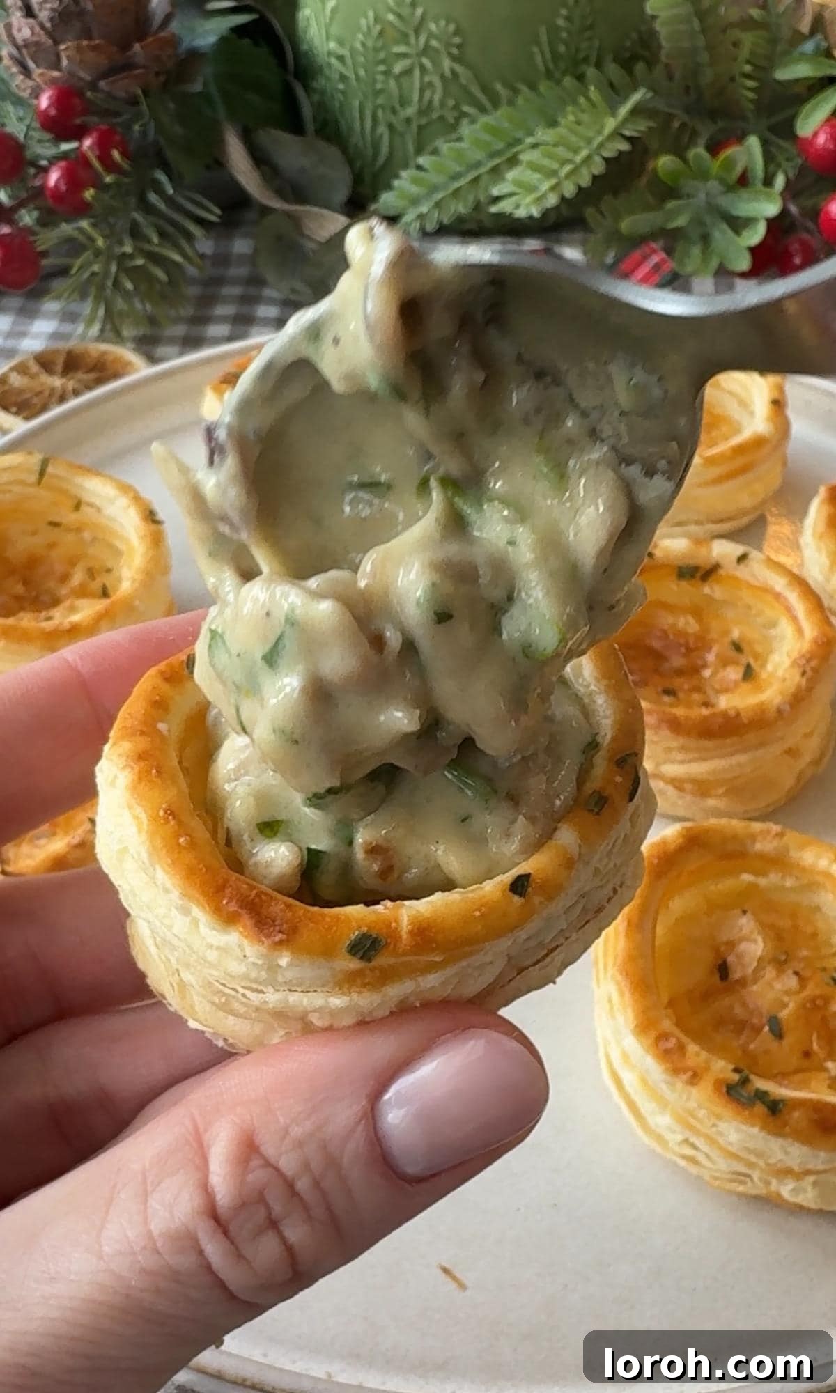 Warm chicken and mushroom filling being carefully spooned into the golden, hollow centers of baked vol-au-vent pastry cases.